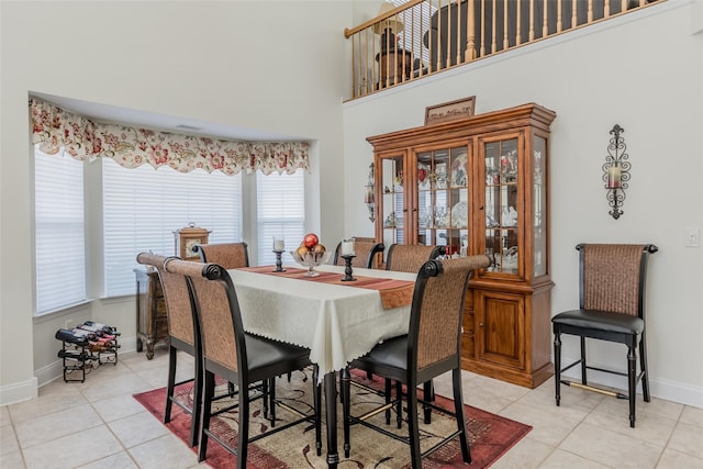 dining space featuring light tile patterned floors, a towering ceiling, and baseboards