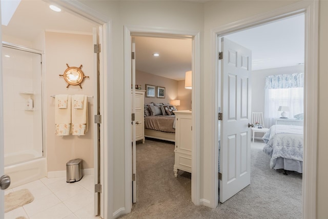 hallway featuring light carpet, light tile patterned floors, and baseboards