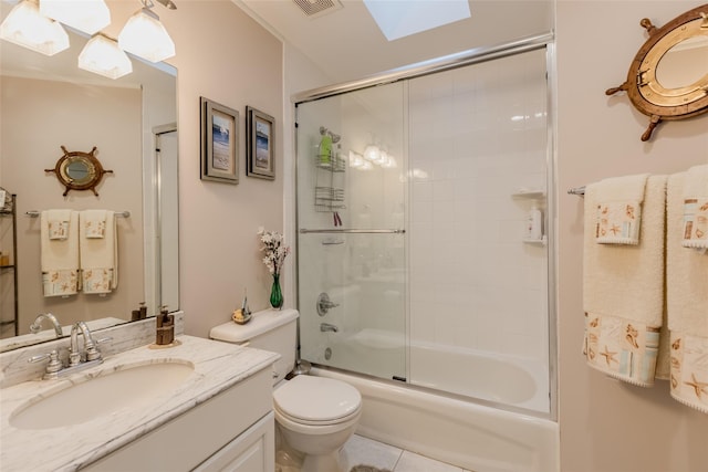 full bathroom featuring bath / shower combo with glass door, a skylight, vanity, and toilet