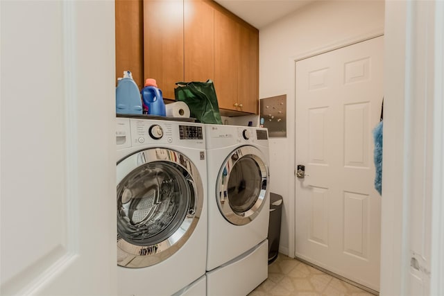 washroom featuring light floors, cabinet space, and washing machine and clothes dryer