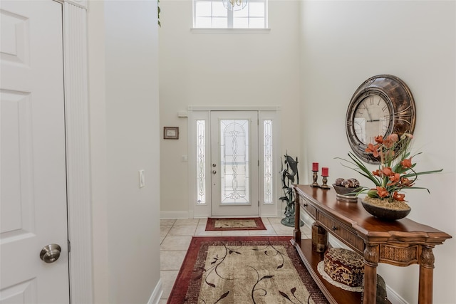 foyer with light tile patterned floors, a high ceiling, and baseboards