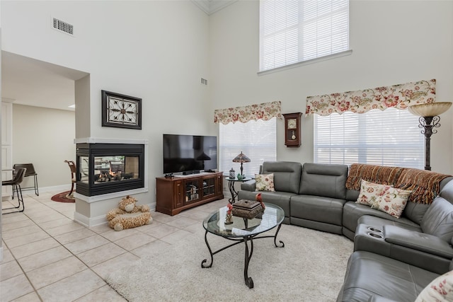 living area featuring baseboards, visible vents, a multi sided fireplace, and light tile patterned flooring