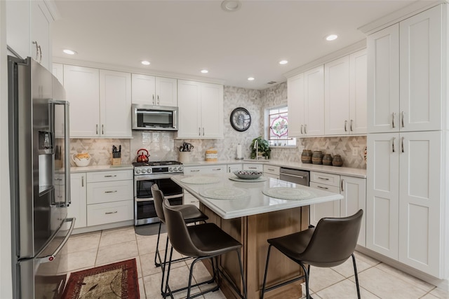 kitchen featuring a breakfast bar, stainless steel appliances, light countertops, and light tile patterned flooring