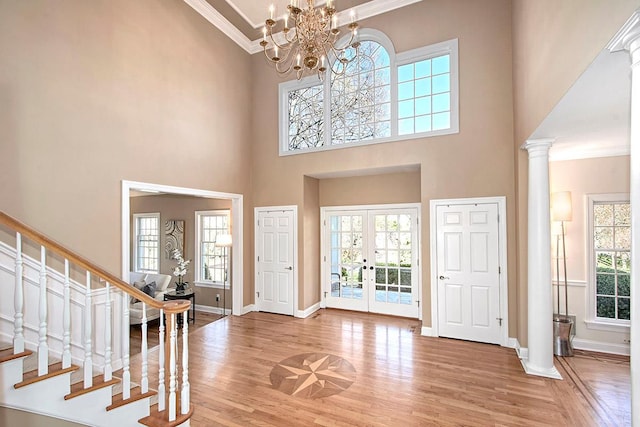 entrance foyer featuring ornate columns, stairway, wood finished floors, and french doors