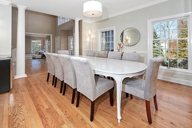 dining area with decorative columns, visible vents, baseboards, crown molding, and light wood-style floors