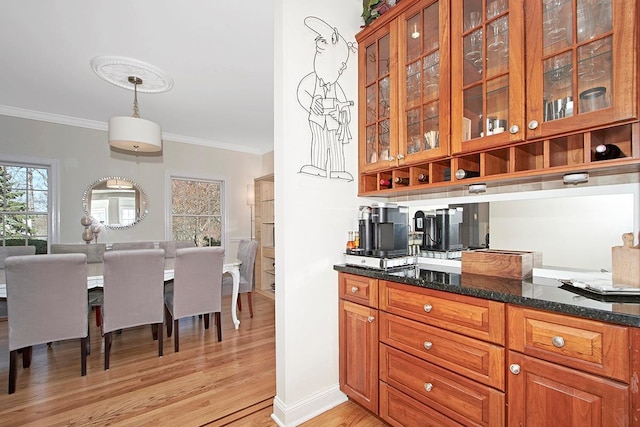 bar featuring baseboards, hanging light fixtures, light wood-type flooring, and crown molding