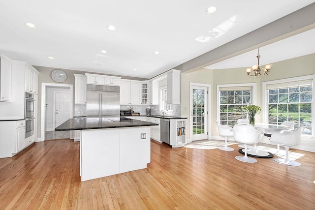 kitchen with light wood-style floors, white cabinetry, stainless steel appliances, and decorative backsplash