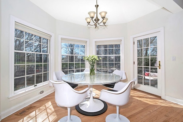 dining room with baseboards, light wood finished floors, visible vents, and an inviting chandelier