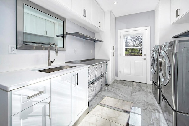 laundry room with cabinet space, baseboards, washing machine and clothes dryer, marble finish floor, and a sink