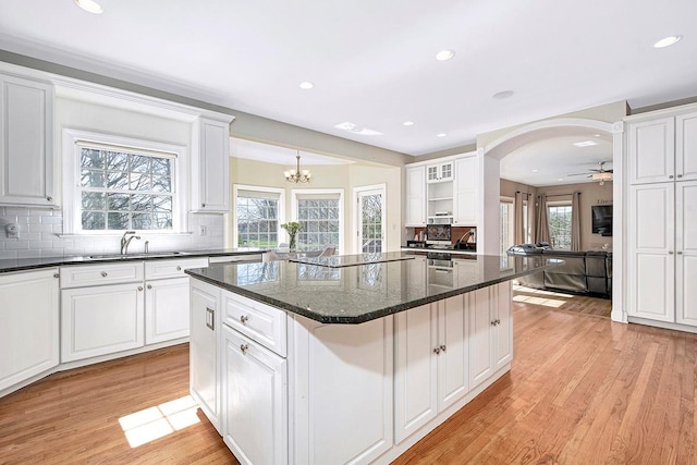 kitchen featuring light wood-style floors, a center island, black electric cooktop, and white cabinetry