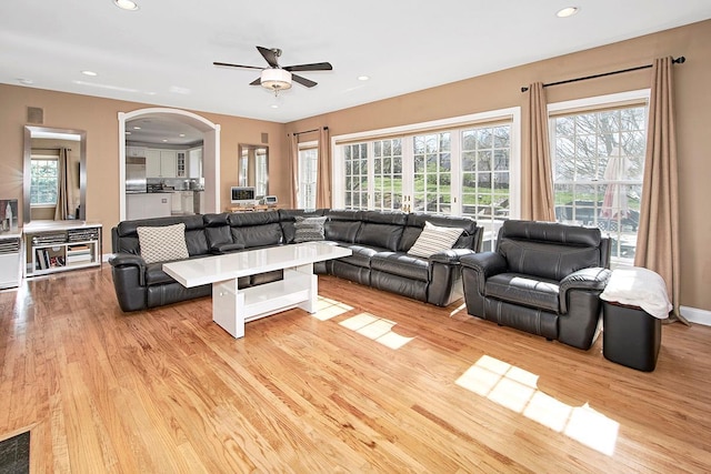 living room featuring light wood-type flooring, arched walkways, a wealth of natural light, and recessed lighting