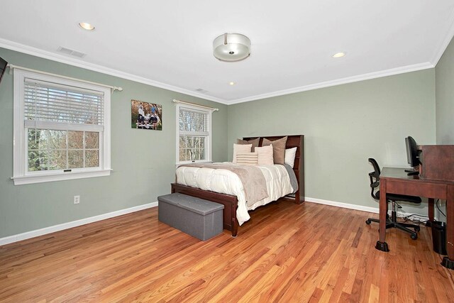 bedroom featuring light wood-type flooring, multiple windows, and crown molding