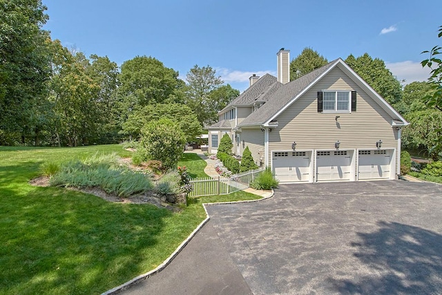 view of side of home featuring aphalt driveway, a chimney, a lawn, an attached garage, and fence