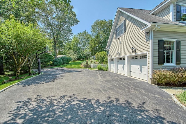 view of home's exterior with an attached garage, driveway, and roof with shingles