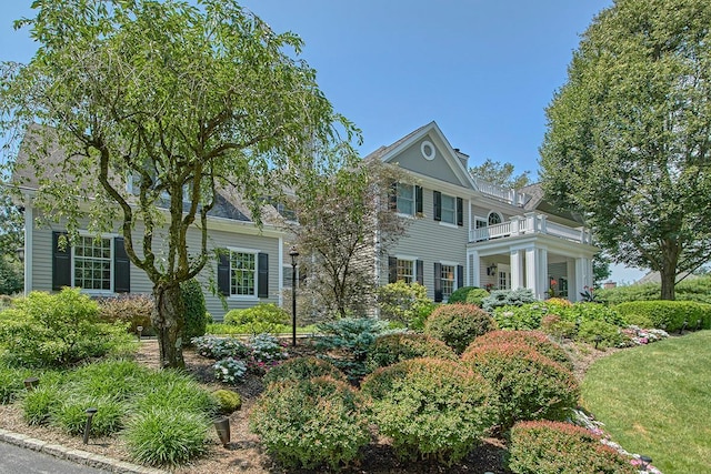 greek revival inspired property featuring a front lawn and a balcony