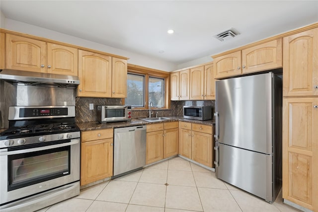 kitchen featuring under cabinet range hood, light brown cabinets, appliances with stainless steel finishes, and a sink