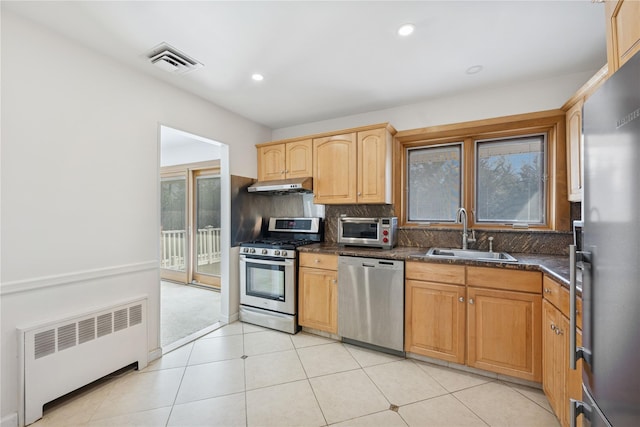 kitchen with visible vents, radiator, stainless steel appliances, under cabinet range hood, and a sink