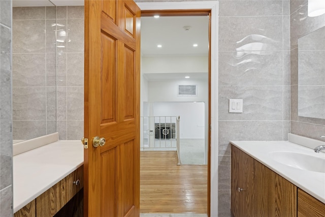 bathroom with visible vents, tile walls, vanity, and wood finished floors