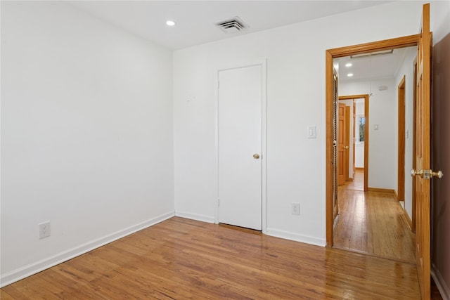 unfurnished bedroom with attic access, baseboards, visible vents, wood finished floors, and recessed lighting