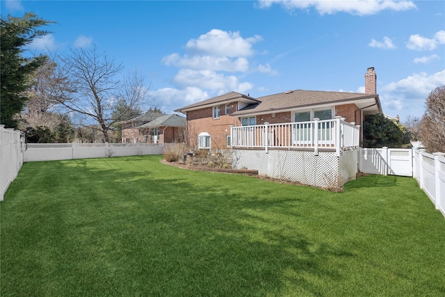 rear view of property featuring a chimney, brick siding, a lawn, and a fenced backyard