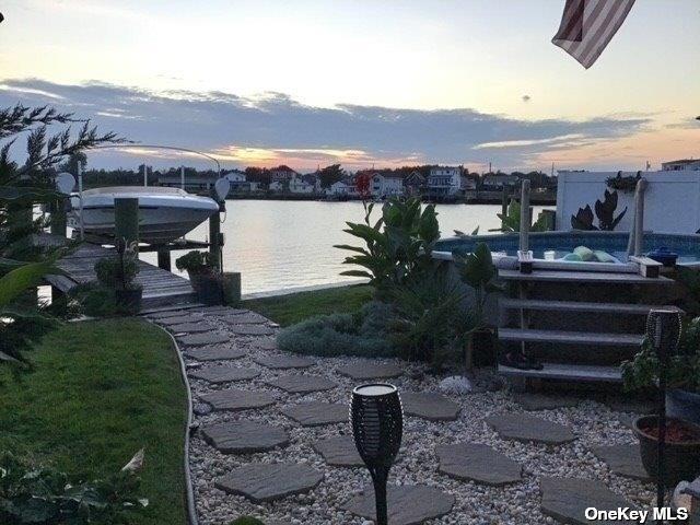 view of dock featuring a water view, an outdoor pool, and boat lift