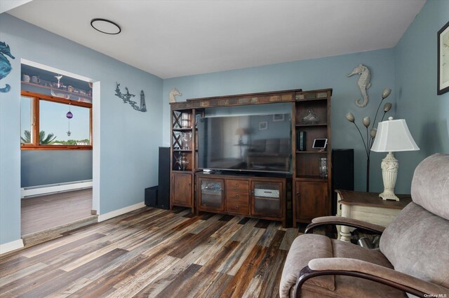 living room featuring a baseboard heating unit, baseboards, and wood finished floors