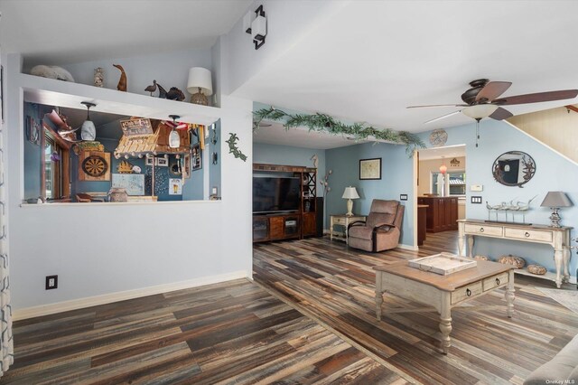 living room featuring a ceiling fan, vaulted ceiling, baseboards, and wood finished floors