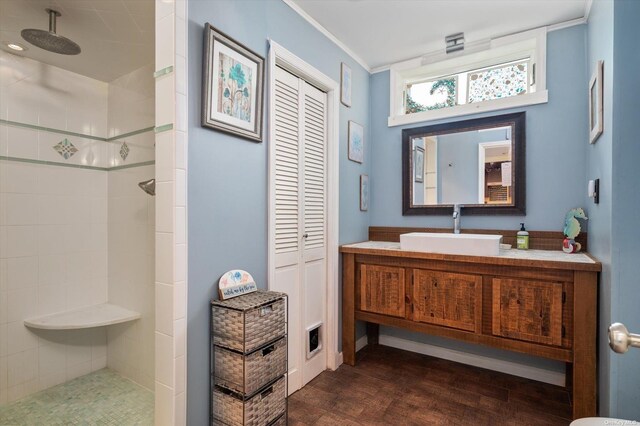 bathroom featuring wood finished floors, a closet, a tile shower, and vanity