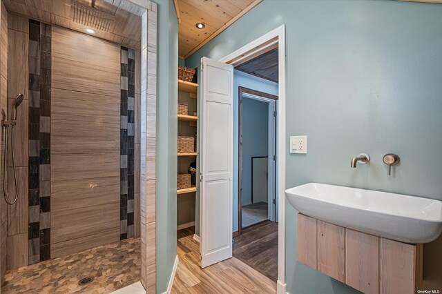 full bathroom featuring wood ceiling, a tile shower, and wood finished floors