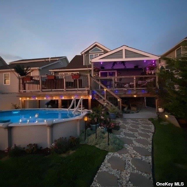 rear view of property with a deck and an outdoor pool