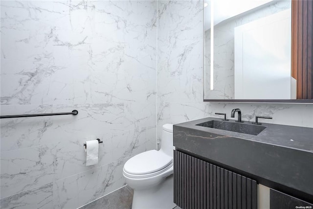 bathroom featuring vanity, toilet, and tile walls