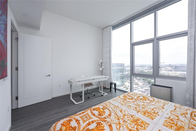 bedroom with a city view, baseboards, a wall of windows, and wood finished floors