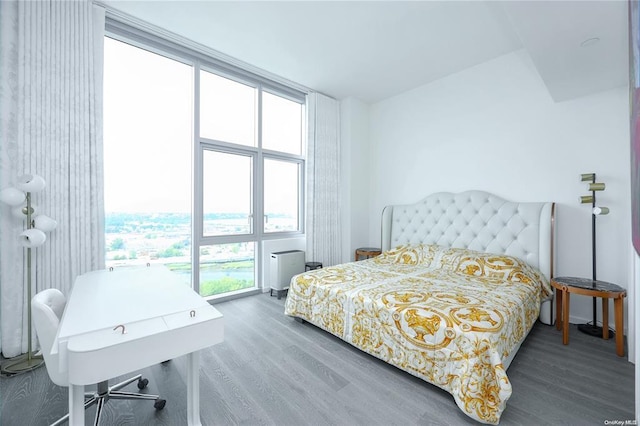 bedroom with a wall of windows and wood finished floors