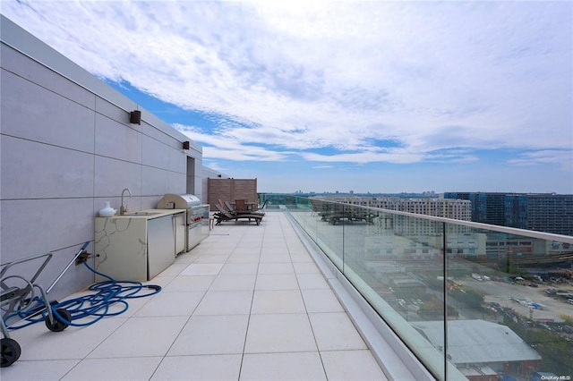 balcony featuring grilling area, an outdoor kitchen, a sink, and a city view