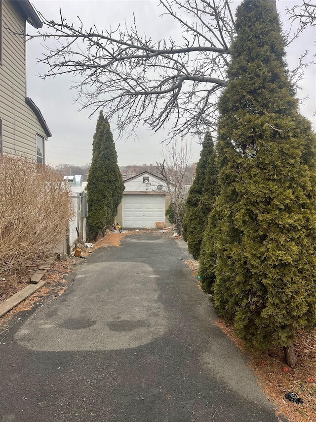 view of side of property with aphalt driveway, an outbuilding, and a detached garage