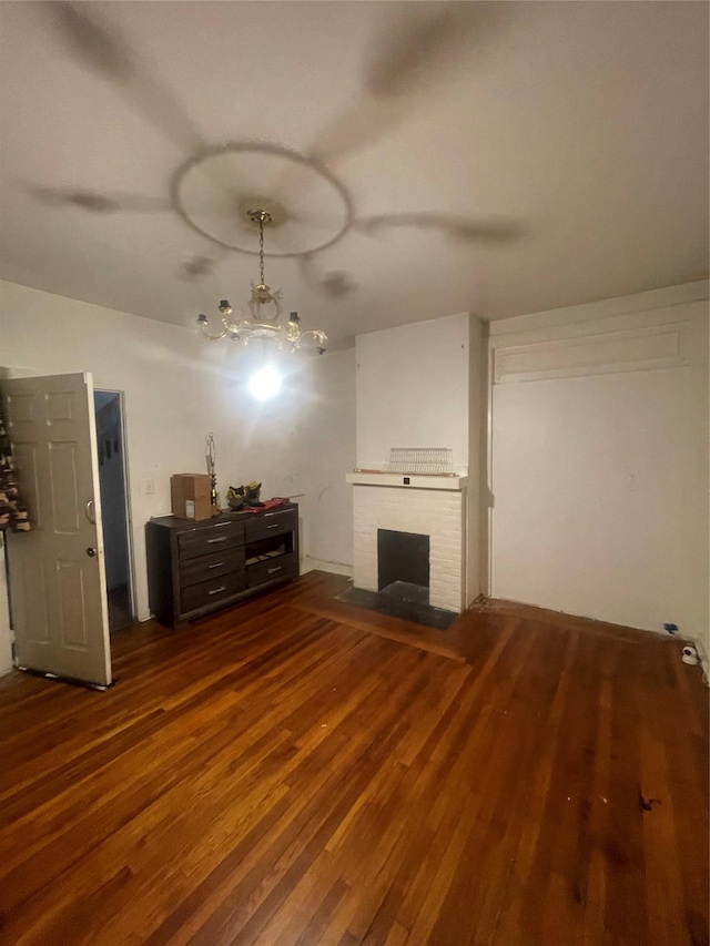 unfurnished living room featuring a fireplace, wood finished floors, and a notable chandelier