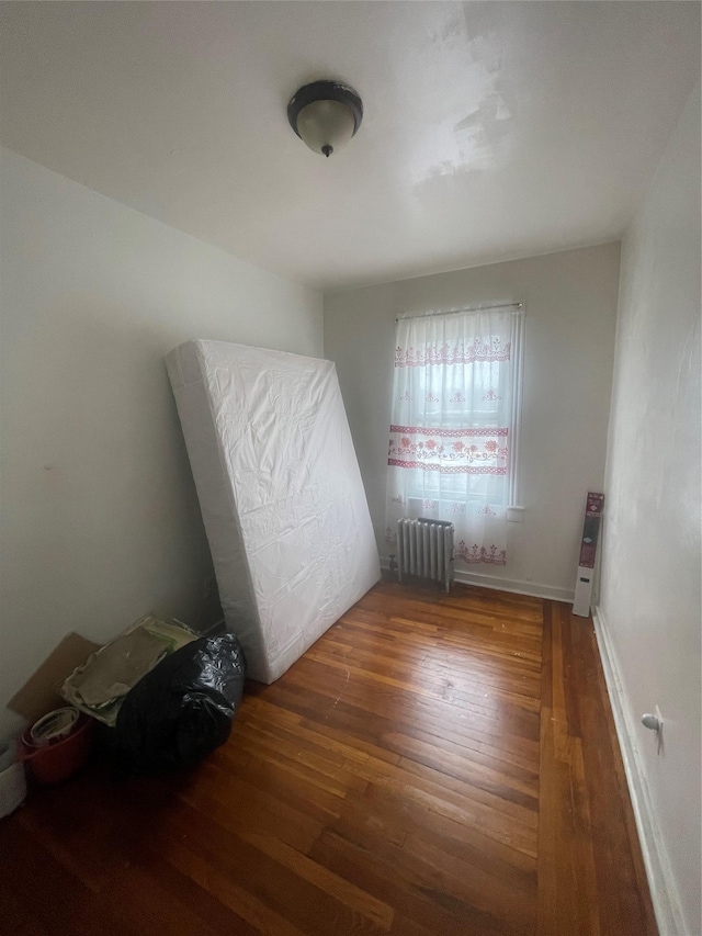 bedroom featuring radiator, baseboards, and wood finished floors