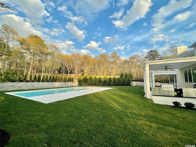 view of yard with an outdoor kitchen, an outdoor pool, ceiling fan, and a patio