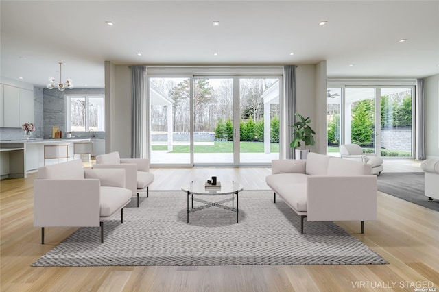 living area featuring a healthy amount of sunlight, light wood-style floors, recessed lighting, and an inviting chandelier