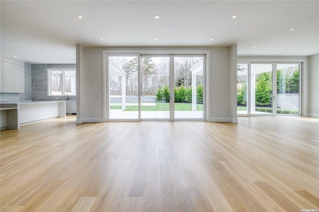 unfurnished living room with baseboards, light wood-style flooring, and recessed lighting