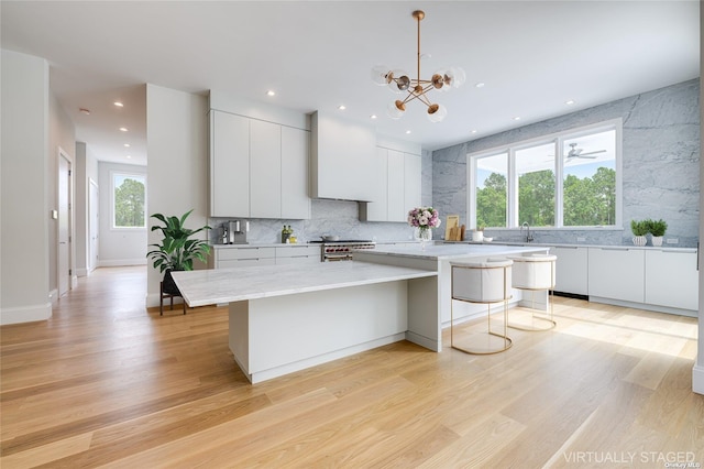 kitchen with modern cabinets, custom range hood, high end stove, and light wood-style flooring