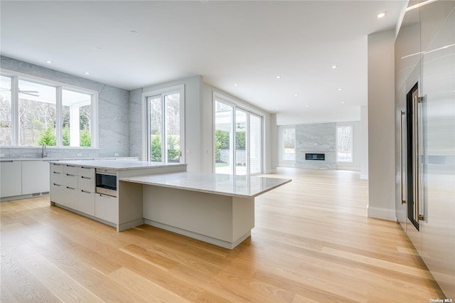 kitchen featuring white cabinetry, light wood-style flooring, modern cabinets, and a fireplace