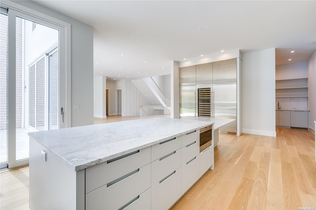 kitchen featuring recessed lighting, modern cabinets, built in microwave, and light wood-type flooring