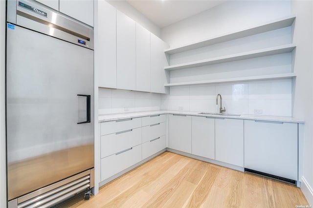 kitchen with open shelves, light countertops, a sink, and built in refrigerator