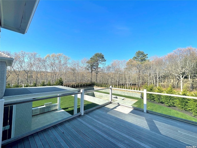 wooden terrace with a view of trees and a lawn