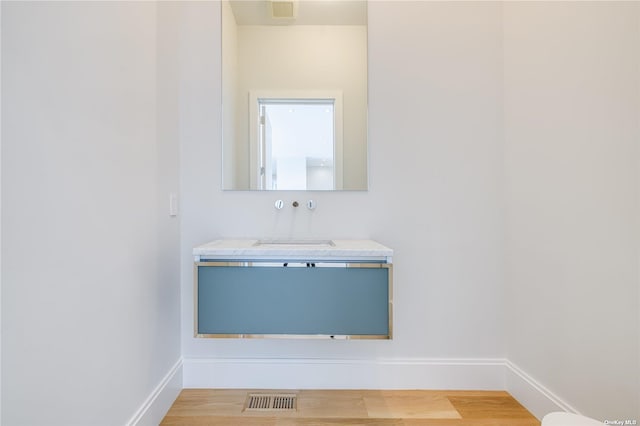 bathroom featuring baseboards, visible vents, vanity, and wood finished floors