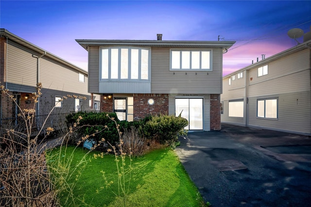 back of house at dusk with brick siding and driveway