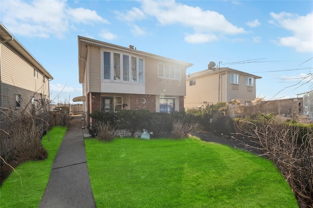 view of front of home featuring brick siding, fence, and a front yard