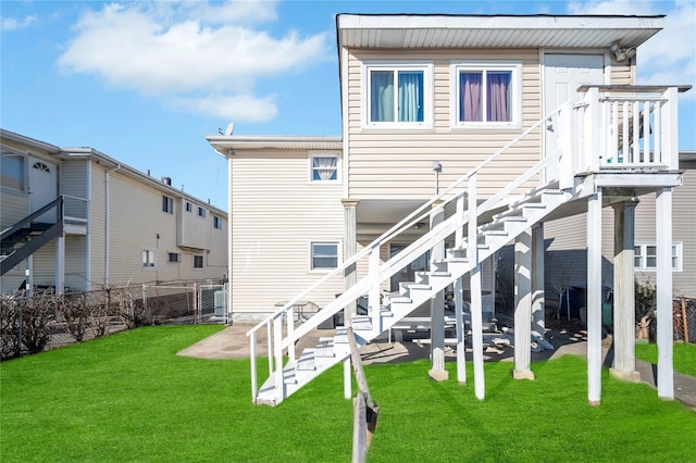 rear view of house with stairs, fence, a lawn, and a patio