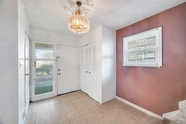 foyer with baseboards, light tile patterned flooring, and an inviting chandelier